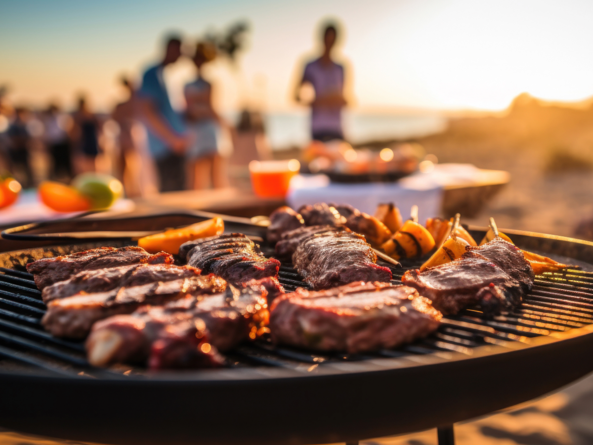 Grill with food on it and people in the background.