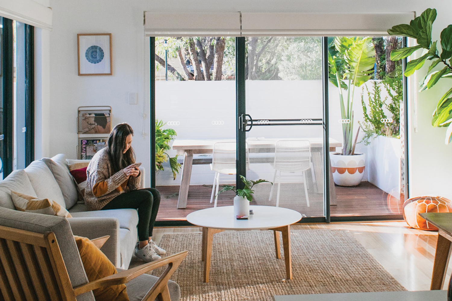 Woman sitting on couch looking at her phone in her living room