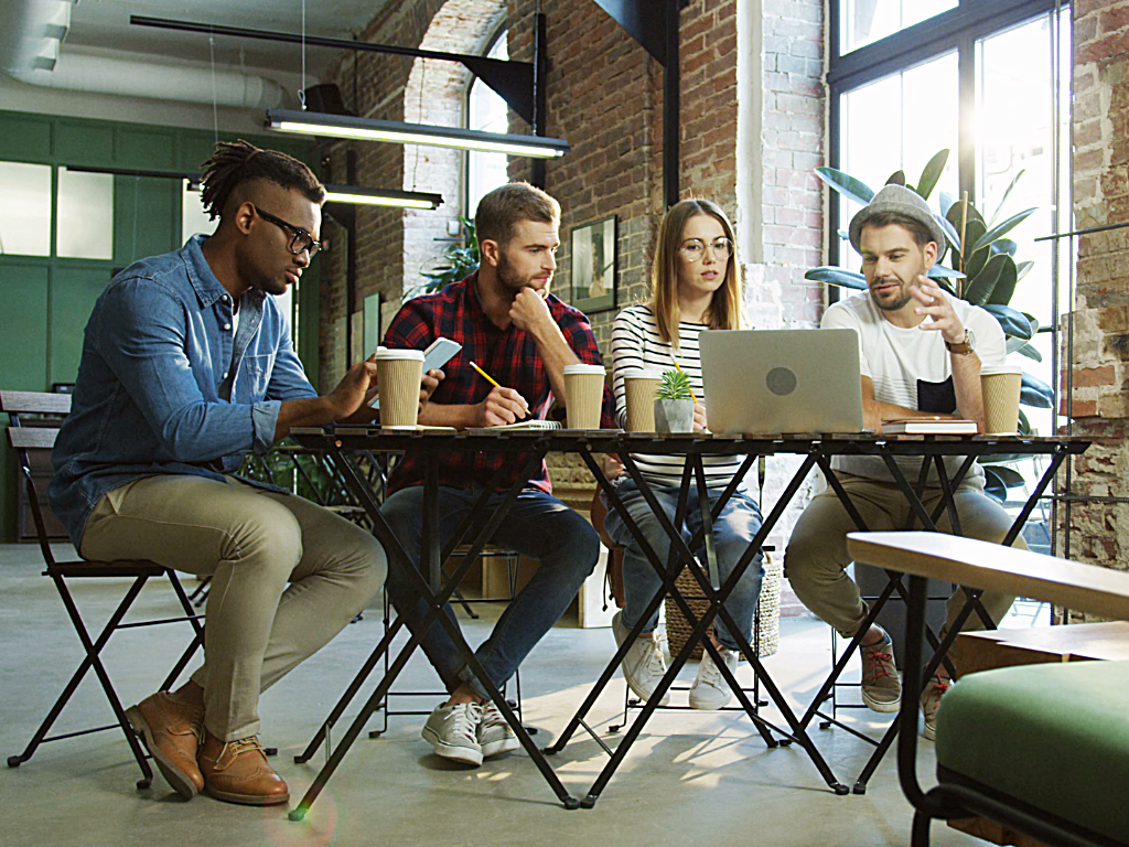 4 young professionals sitting around a big table planning startup.