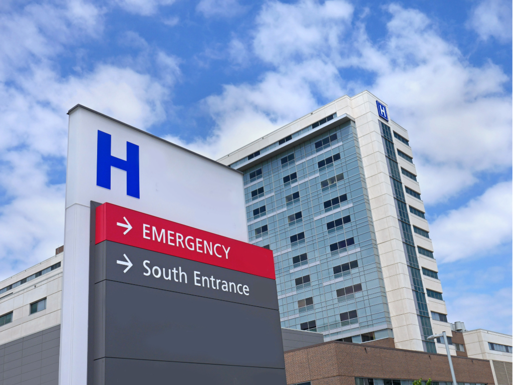 Outside picture of Hospital showing directional signage for emergency room.